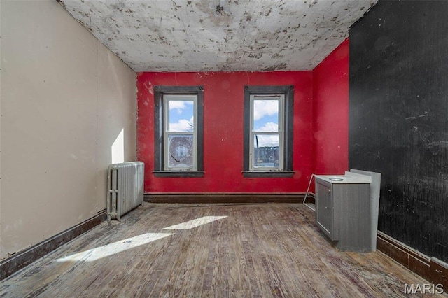 7307 Minnesota Ave, Saint Louis, MO 63111 - spare room featuring radiator heating unit, wood finished floors, and baseboards