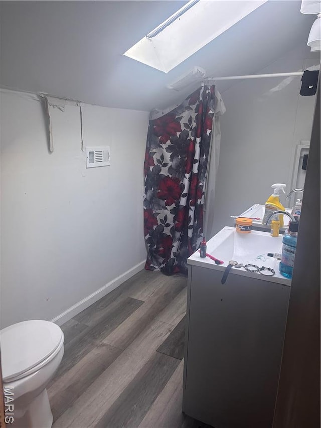 4600 Carrie Ave, Saint Louis, MO 63115 - bathroom featuring a skylight, wood finished floors, toilet, curtained shower, and baseboards