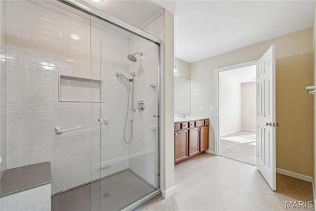 full bathroom featuring a stall shower, vanity, baseboards, and tile patterned flooring