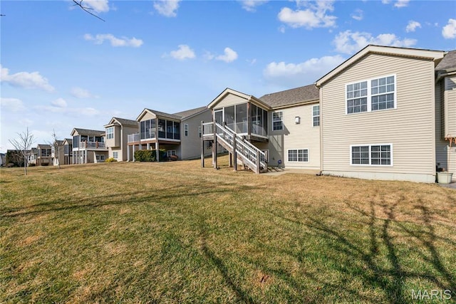 back of property featuring a sunroom, a yard, and a residential view