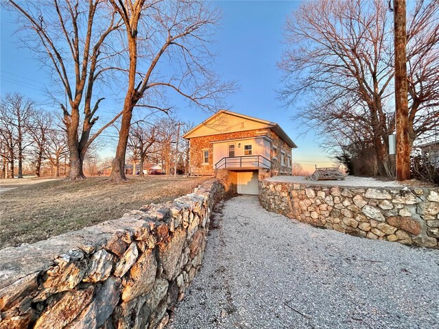 601 S Grand St, Salem, MO 65560 - view of home's exterior featuring stone siding, gravel driveway, and a balcony
