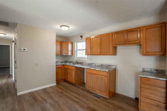 20 W Broadway, Ellsinore, MO 63937 - kitchen featuring a sink, wood finished floors, brown cabinetry, and baseboards