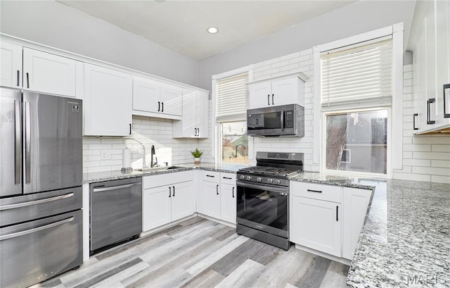 2922 S Compton Ave, Saint Louis, MO 63118 - kitchen with stainless steel appliances, a sink, white cabinetry, decorative backsplash, and light stone countertops