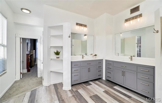 2922 S Compton Ave, Saint Louis, MO 63118 - bathroom with wood finished floors, two vanities, and baseboards
