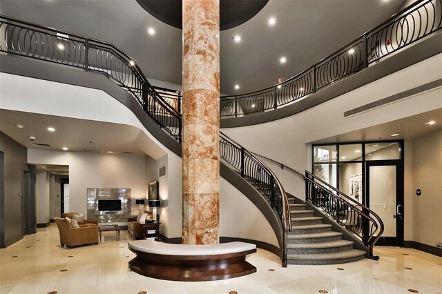 155 Carondelet Plz Unit 600, Saint Louis, MO 63105 - staircase featuring a towering ceiling, ornate columns, baseboards, and tile patterned floors