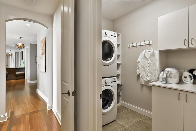 155 Carondelet Plz Unit 600, Saint Louis, MO 63105 - laundry area featuring stacked washing machine and dryer, cabinet space, arched walkways, and baseboards
