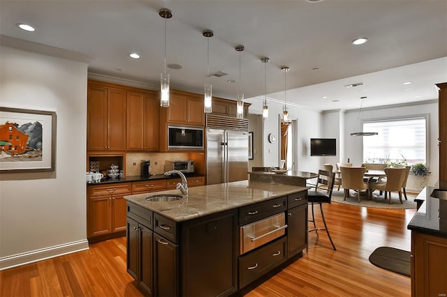 155 Carondelet Plz Unit 600, Saint Louis, MO 63105 - kitchen featuring built in appliances, wood finished floors, a sink, a kitchen breakfast bar, and tasteful backsplash