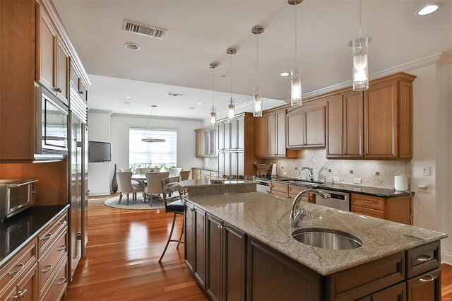155 Carondelet Plz Unit 600, Saint Louis, MO 63105 - kitchen featuring a sink, a center island with sink, wood finished floors, backsplash, and recessed lighting