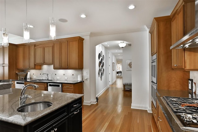 155 Carondelet Plz Unit 600, Saint Louis, MO 63105 - kitchen featuring a sink, wall chimney exhaust hood, light wood-style floors, arched walkways, and appliances with stainless steel finishes