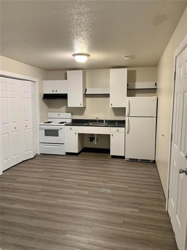 kitchen with white appliances, a sink, under cabinet range hood, white cabinetry, and dark wood-style floors