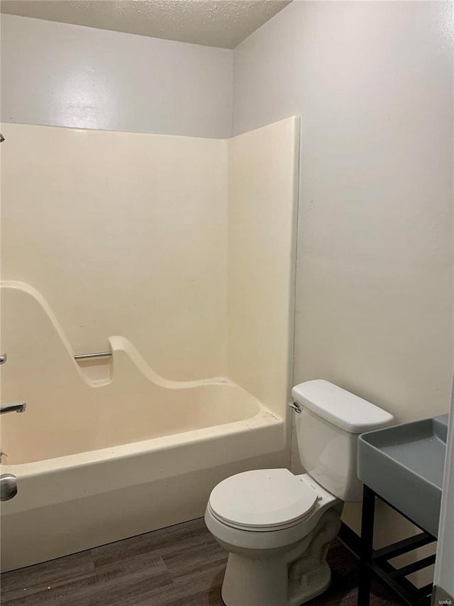 full bath with wood finished floors, toilet, and a textured ceiling