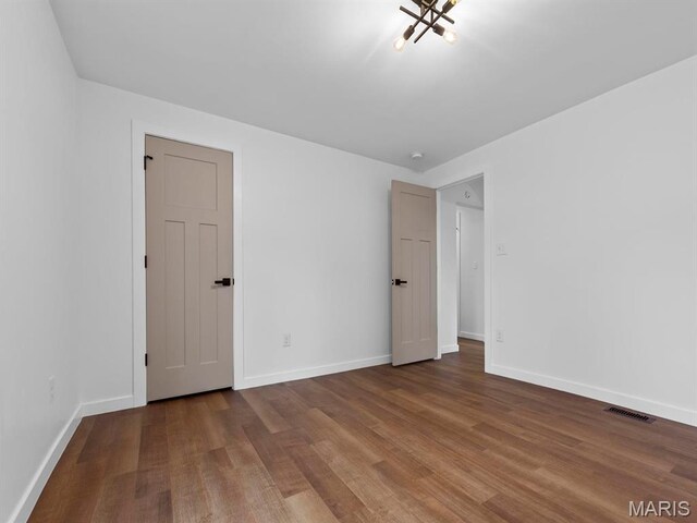 6634 Chamberlain Ave, University City, MO 63130 - unfurnished bedroom featuring wood finished floors, baseboards, and a chandelier