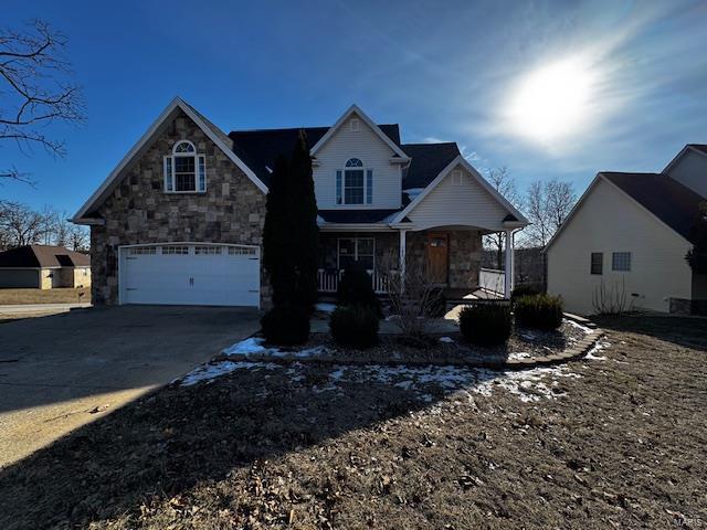 100 Walnut Ct, Saint Robert, MO 65584 - view of front of property with stone siding, covered porch, a garage, and concrete driveway