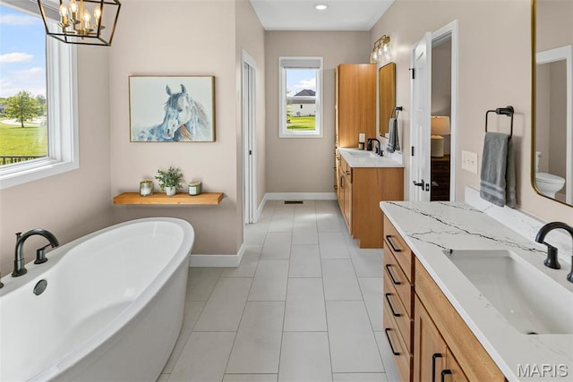 3837 Tanzanite Trl, Edwardsville, IL 62025 - bathroom with two vanities, baseboards, a chandelier, a soaking tub, and toilet