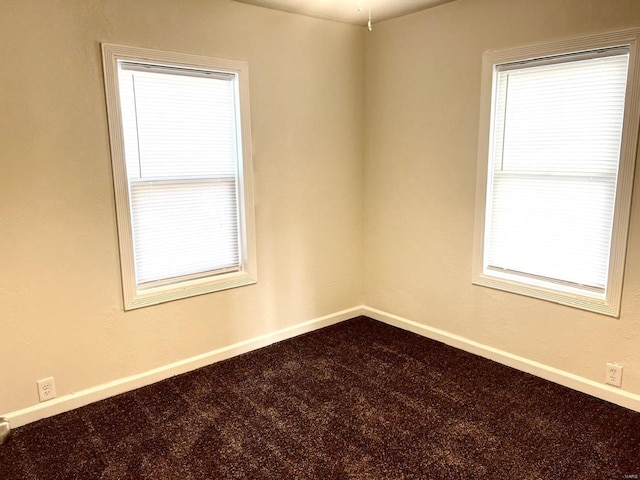 empty room with baseboards and dark colored carpet