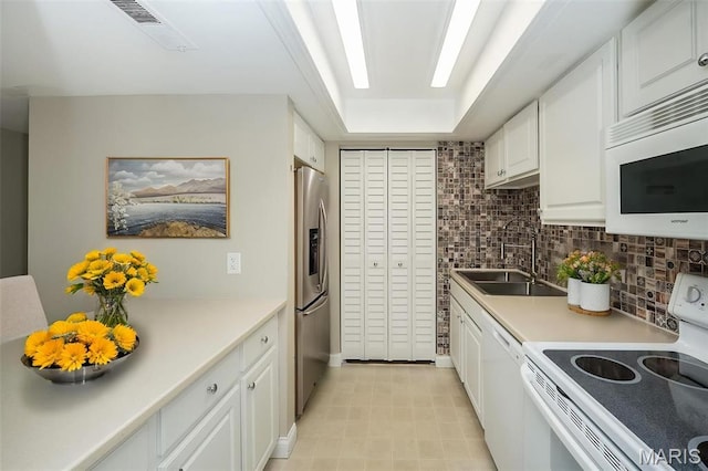kitchen featuring white appliances, a sink, white cabinets, decorative backsplash, and light countertops