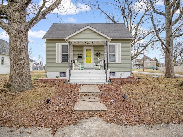 bungalow featuring a porch and roof with shingles