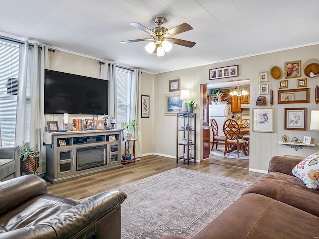 living area with ceiling fan, wood finished floors, baseboards, and a chandelier