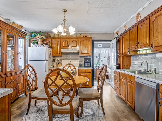 kitchen with stainless steel dishwasher, a sink, range, under cabinet range hood, and freestanding refrigerator