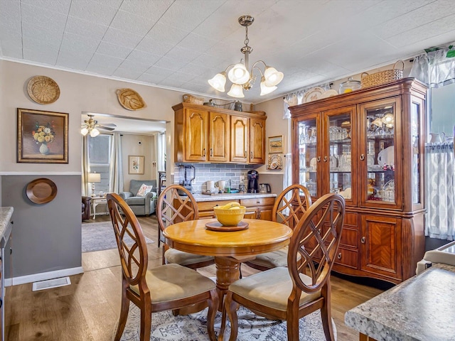 dining space featuring light wood-style flooring, a chandelier, and ornamental molding