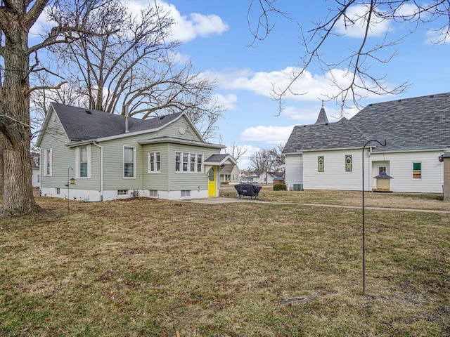 back of house with a yard and roof with shingles