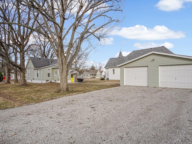 view of property exterior with gravel driveway, a residential view, a garage, and a yard
