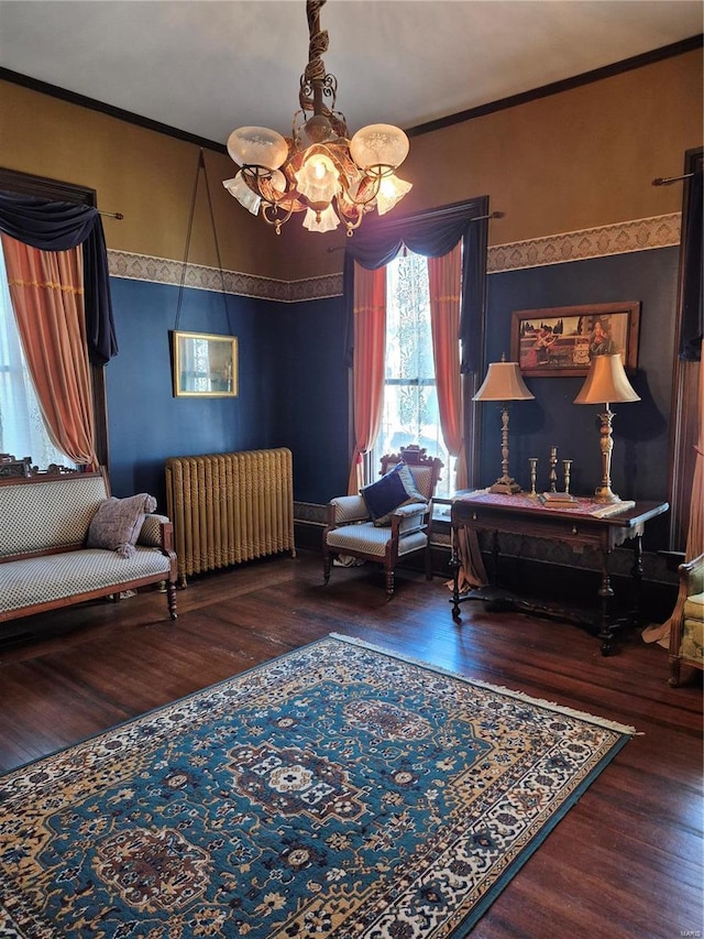 sitting room featuring radiator, a chandelier, ornamental molding, and wood finished floors