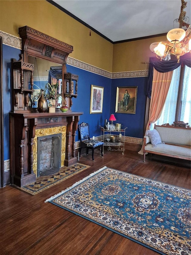 living area with crown molding, wood finished floors, a fireplace, and a chandelier