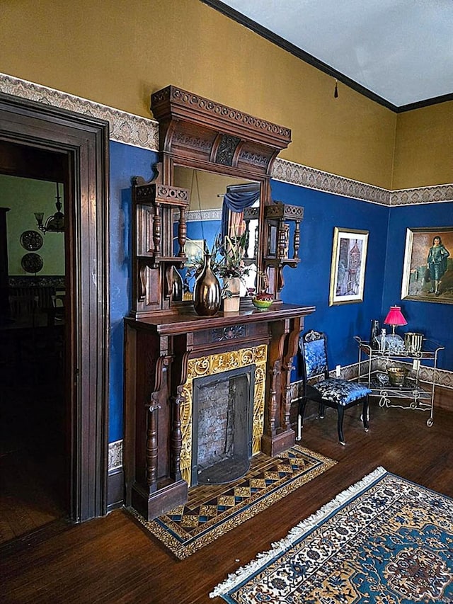 living area featuring wood finished floors, crown molding, and a fireplace