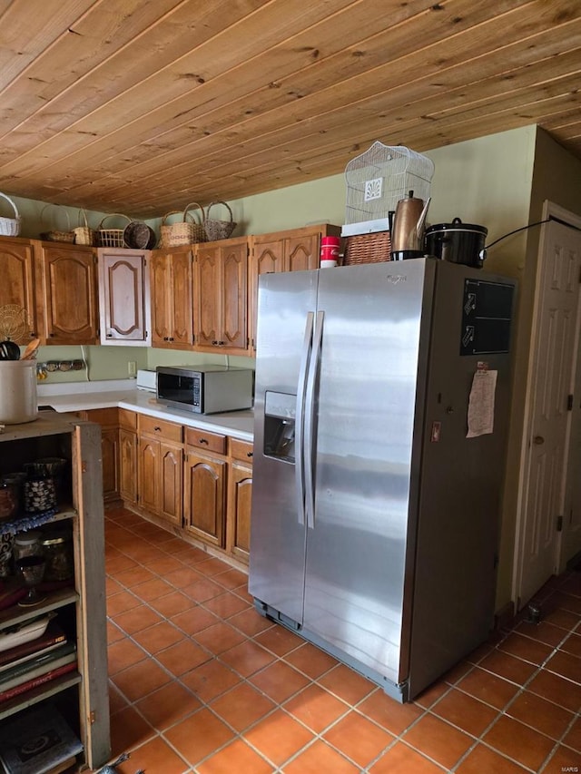 kitchen with appliances with stainless steel finishes, tile patterned flooring, brown cabinets, light countertops, and wooden ceiling