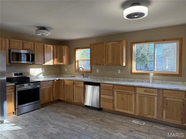 134 N 82nd St, Belleville, IL 62223 - kitchen featuring appliances with stainless steel finishes, a sink, and light wood finished floors