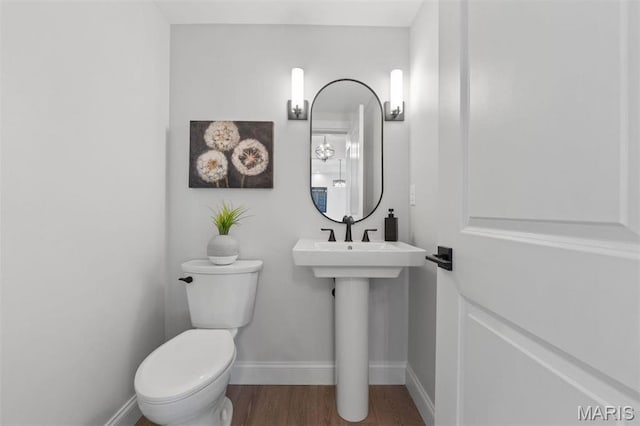 bathroom with baseboards, wood finished floors, and toilet