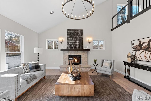 living area featuring high vaulted ceiling, a fireplace, wood finished floors, healthy amount of natural light, and a chandelier