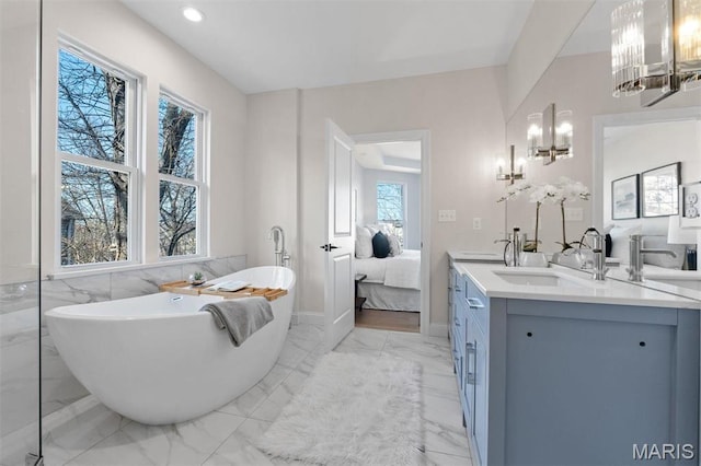 ensuite bathroom with a chandelier, marble finish flooring, a soaking tub, vanity, and recessed lighting