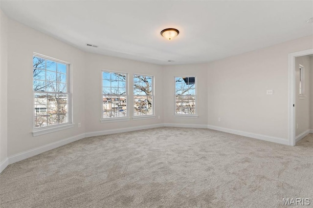 empty room featuring plenty of natural light, carpet flooring, and baseboards
