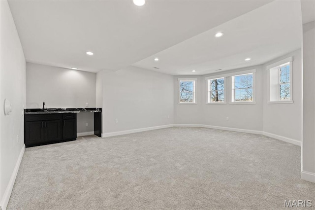 basement featuring light colored carpet, baseboards, recessed lighting, and wet bar
