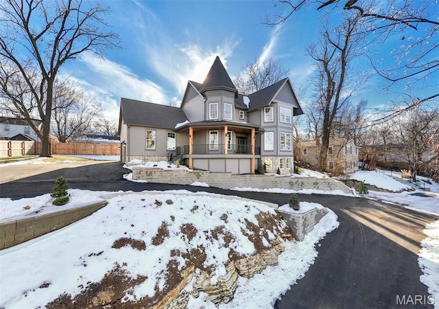 victorian house featuring fence and a porch