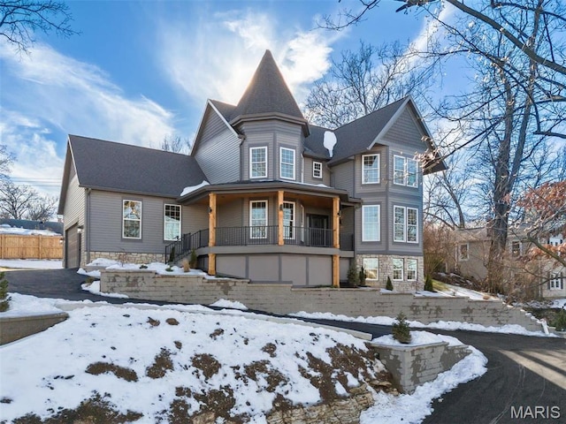 victorian home with stone siding, covered porch, and a garage