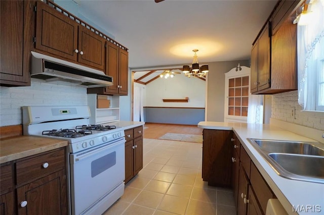 1014 Jefferson St, Hermann, MO 65041 - kitchen featuring white gas stove, under cabinet range hood, a chandelier, decorative backsplash, and light countertops