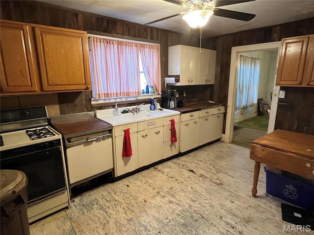 3620 Thomas Ave, Alton, IL 62002 - kitchen featuring gas stove, wooden walls, a ceiling fan, and brown cabinetry
