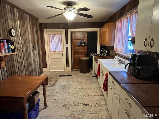 3620 Thomas Ave, Alton, IL 62002 - kitchen featuring a ceiling fan, range with gas stovetop, dark countertops, wood walls, and a sink