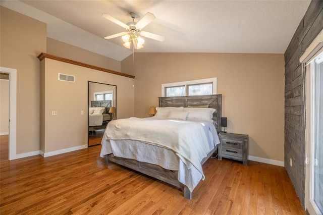 bedroom featuring light wood finished floors, lofted ceiling, baseboards, and ceiling fan