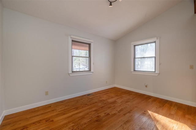 spare room featuring vaulted ceiling, wood finished floors, and baseboards