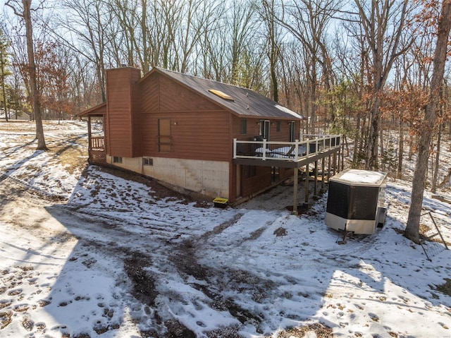 view of snowy exterior featuring a deck and a chimney