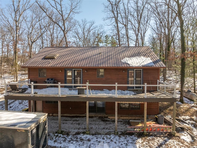 snow covered property with a deck and metal roof