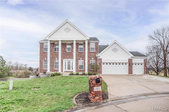 greek revival inspired property with concrete driveway, a front yard, brick siding, and a garage