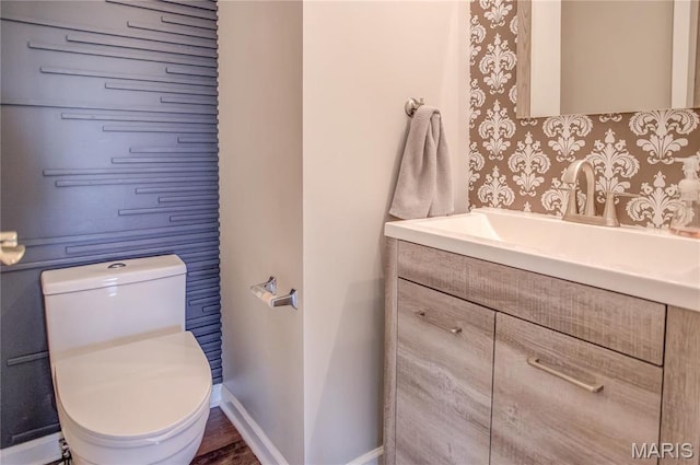 bathroom featuring toilet, vanity, and baseboards