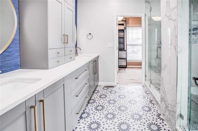 bathroom with a marble finish shower, baseboards, and double vanity
