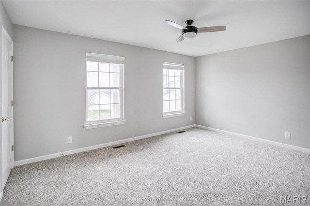 carpeted spare room with plenty of natural light, ceiling fan, and baseboards