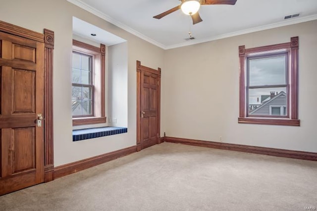 spare room with light colored carpet, baseboards, ornamental molding, and ceiling fan